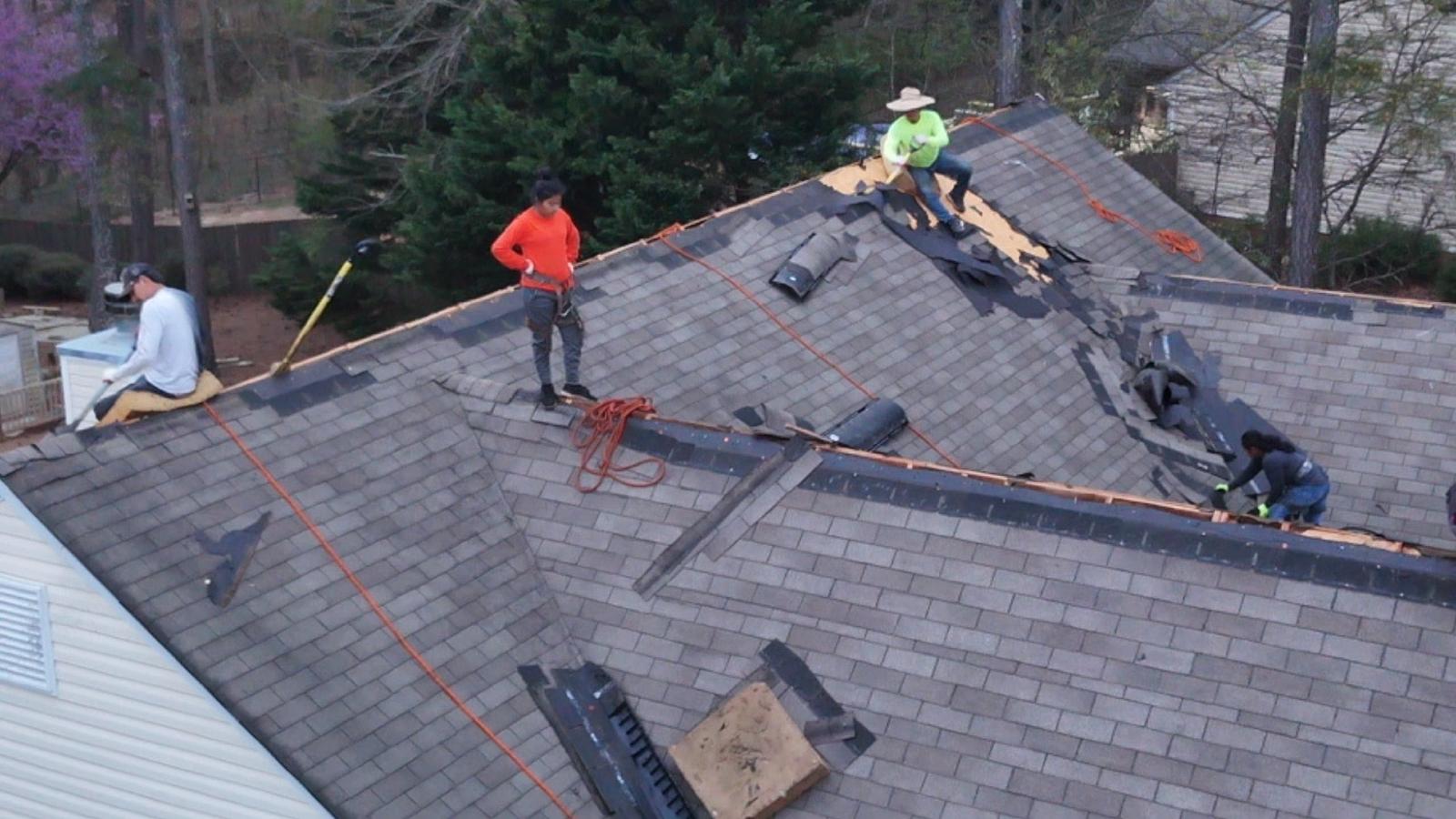 Roofing crew inspecting and installing shingles on a residential roof